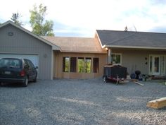 a car is parked in front of a house that has been built into the gravel