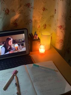 a laptop computer sitting on top of a wooden desk next to a notebook and pen