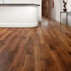 an empty room with wood flooring and a white reception table in the center,