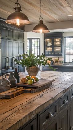 a large kitchen with wooden counter tops and hanging lights over the island, surrounded by gray cabinets