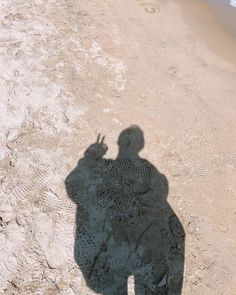 a shadow of a person on the beach with a skateboard in his hand,