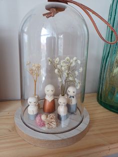 some little figurines under a glass dome with flowers