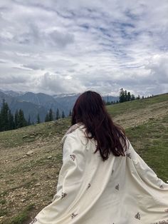 a woman sitting on top of a hill covered in a blanket