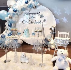 a table with balloons and decorations for a baby's first birthday party in blue, white and silver