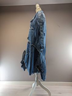 a blue jean jacket on a stand in front of a gray wall