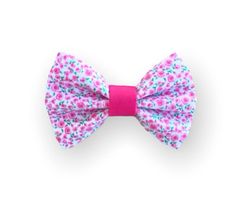 a pink bow tie with blue and pink flowers on the front, sitting on a white surface