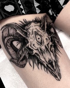 a black and white photo of a ram's head tattoo on the side of a woman's thigh