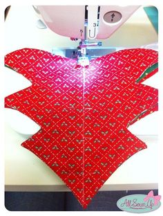 the sewing machine is making a heart shape out of sequins and fabric material