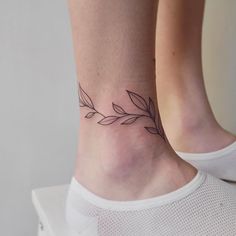 a woman's foot with a small tattoo on the ankle that has leaves growing out of it