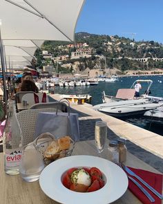 a white plate topped with food on top of a wooden table next to the ocean