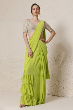 Lime green draped saree with placement rhinestone embellishment. Paired with a silver padded rhinestone embellished blouse.
Components: 2
Pattern: Blouse: Embellished
Type Of Work: Rhinestone
Neckline: V Neck
Sleeve Type: Half Sleeves
Fabric: Silk Georgette: Saree, Tissue: Blouse 
Color: Green
Other Details: 
Padded and scallop trim blouse
Attached inner lining
Length: (in inches)
Saree: 44
Blouse: 14
Pleat and ruffle detail pallu
Occasion: Sangeet - Aza Fashions Georgette Saree Blouse, Green Drapes, Draped Saree, Drape Saree, Silver Silk, Embellished Blouse, Scallop Trim, Pattern Blouse, Georgette Saree