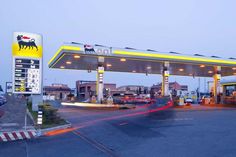 a gas station at dusk with cars passing by