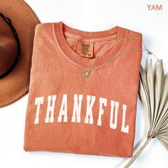 Celebrate Thanksgiving in style with this Thankful shirt, perfect as a family matching holiday outfit for Thanksgiving dinner or fall festivals. This plus size fall festival and autumn Thanksgiving shirt makes a great Friendsgiving host gift or a thoughtful present for teachers, moms, and dads. GOBBLE 'TIL YOU WOBBLE IN OUR FESTIVE THANKSGIVING TEE!  * Celebrate Turkey Day in style with our fun and festive "TURKEY DAY" graphic tee, featuring adorable cartoon turkeys.  * Perfect for family photos Thanksgiving Letter Print Cotton Tops, Fall Cotton Tops With Lettering, Letter Print T-shirt As Fall Gift, Brown Letter Print T-shirt For Fall, Cotton T-shirt For Fall Holiday, Fall Short Sleeve Tops For Gift, Fall Short Sleeve Tops For Gifts, Graphic Print Tops For Fall Holiday Season, Graphic Print Tops For Holiday In Fall