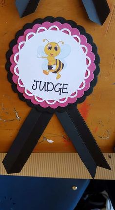 a sign with a bee on it that says,'judge'in front of a wooden background