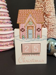 a small wooden house sitting on top of a table next to some christmas tree decorations