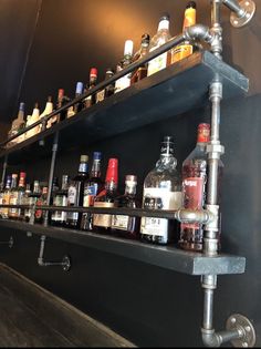 bottles are lined up on the shelves in a bar area with faucets and pipes