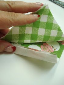 a woman's hand is holding two pieces of green and white paper on top of each other