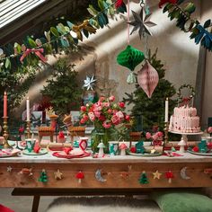 a table topped with lots of cakes and desserts next to christmas tree decorations on top of it