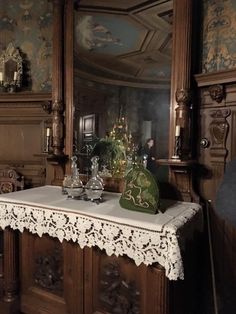 a table topped with glass vases next to a wall covered in ornately decorated walls