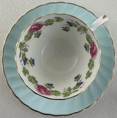 an empty tea cup and saucer sitting on a white tablecloth with blue trim