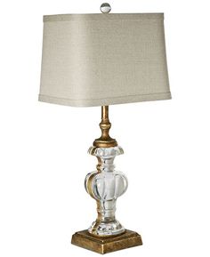 a glass table lamp with a gold base and a white shade on the top of it