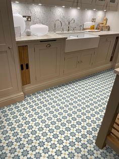 a kitchen with blue and white tile flooring next to a counter top oven, sink and dishwasher