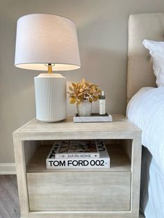 a nightstand with a lamp on it next to a bed