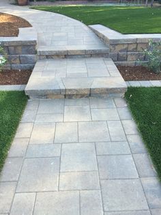 a stone walkway in the middle of some grass