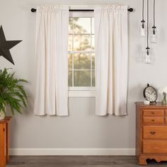 a room with two wooden dressers and a white curtain hanging on the wall above it