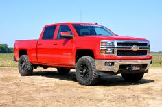 a red truck parked on top of a dirt field