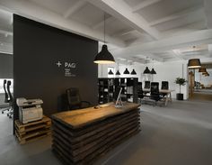 an office with black and white walls, wooden tables and chairs in front of the desks