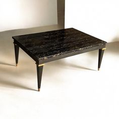 a black marble coffee table sitting on top of a white floor next to a wall