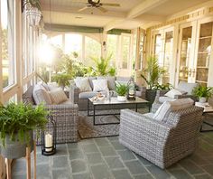 a living room filled with lots of furniture next to a window covered in plants and potted plants