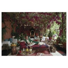 a man sitting on top of a red couch in a living room filled with flowers