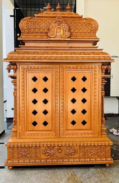 an ornate wooden cabinet with intricate carvings on the front and sides, sitting in a room