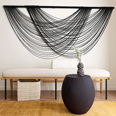 a black vase sitting on top of a wooden floor next to a white couch and table