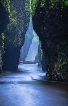 a narrow river surrounded by tall rocks and greenery on both sides with water flowing between them