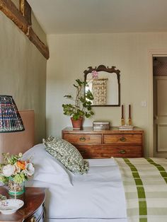 a bedroom with a bed, dresser and mirror on the wall next to each other