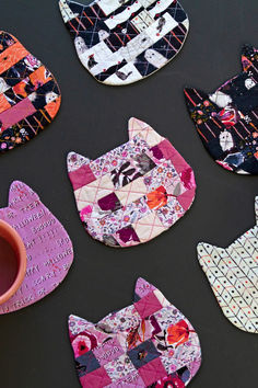 several pieces of quilted cat shaped coasters next to a cup on a table