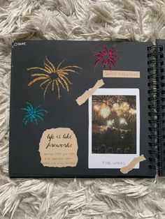 an open notebook with fireworks and pictures on the cover, sitting on a fluffy white blanket