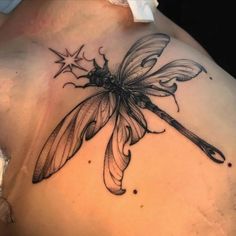 a woman's back with a dragonfly tattoo on it