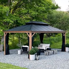 a black and white striped couch under a wooden gazebo in the middle of a gravel area