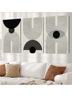 three black and white art pieces hanging on the wall above a couch in a living room