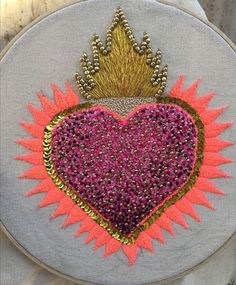 a heart with a crown on it is surrounded by pink and gold beads in the shape of a sunburst