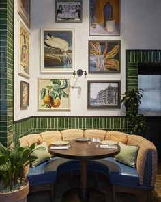 a corner table in front of a booth with pictures on the wall above it and potted plants next to it