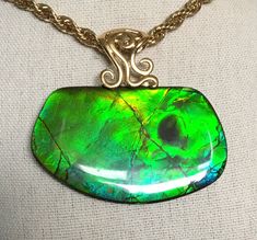 "This Ammolite pendant has a large green gem with golden overtones.  It has a shiny resin coating and measures in at 53mm x 31mm and hangs from a decorative sterling silver bail with gold wash (vermeil),  This gem has either a reverse horn or a bite mark.  Reverse horns show when the ammolite is split from the concretions, and sometime one gets a positive and negative gem surface.  When it is a negative surface, the horn will be reversed.  Bite marks often show loss of gem or a fractured gem area, so likely this is a reverse horn.  At very extreme angles some blue shows, as seen in the third photo.  It comes on an 18\" gold plated chain as shown.  Other lengths may be available on request.  Please remember that I offer combined shipping." Bite Mark, Green Gem, The Horn, Green Gems, Resin Coating, Gold Wash, Positive And Negative, Gold Plated Chains, Opal Rings