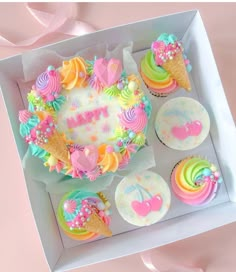 a box filled with cupcakes covered in frosting and rainbow colored icing