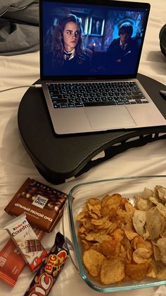 an open laptop computer sitting on top of a table next to chips and chocolates