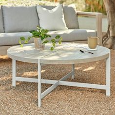 a white coffee table sitting on top of a gravel covered ground next to a couch