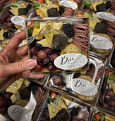 a person holding a tray full of cheeses and crackers with fruit in it